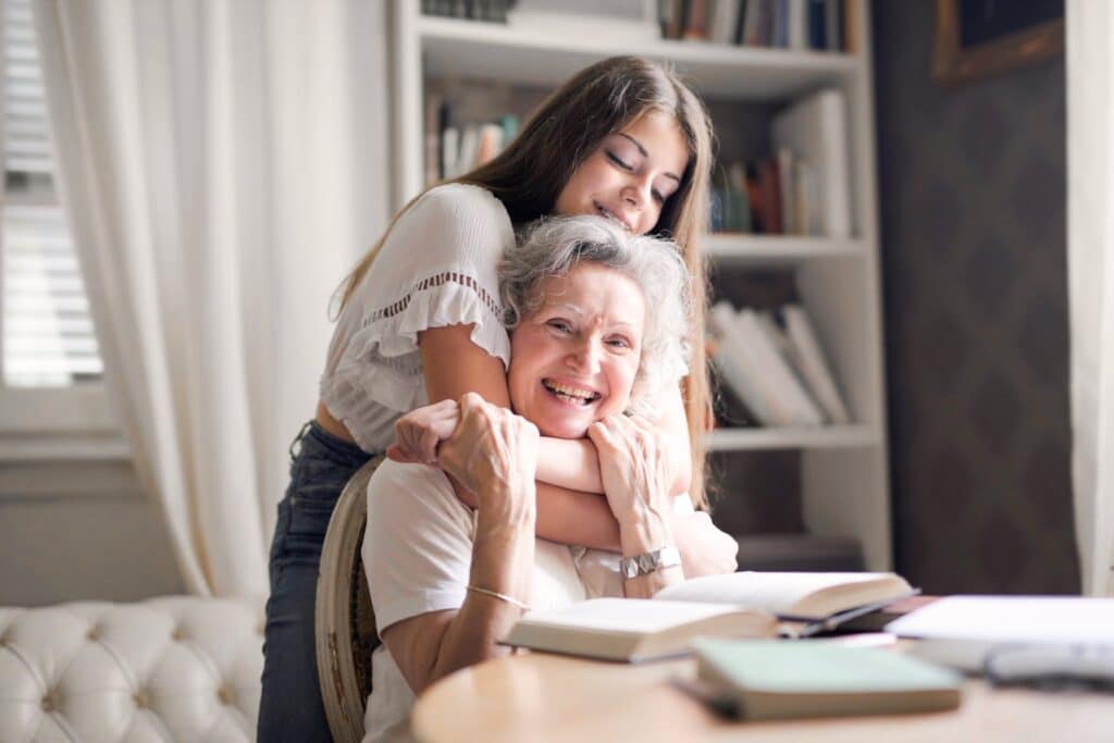 A joyful moment of a grandmother and granddaughter sharing a loving embrace at home.
