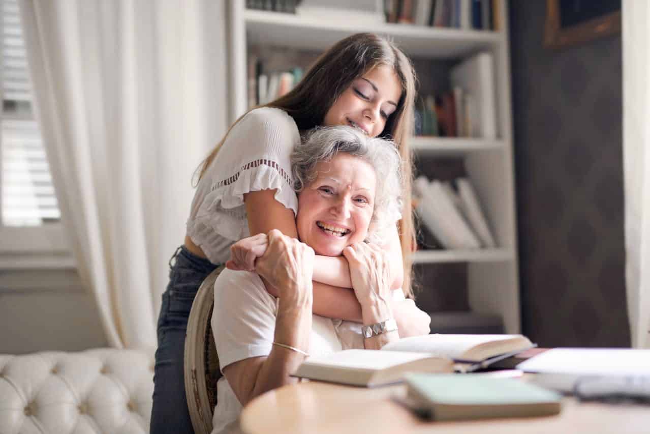 A joyful moment of a grandmother and granddaughter sharing a loving embrace at home.