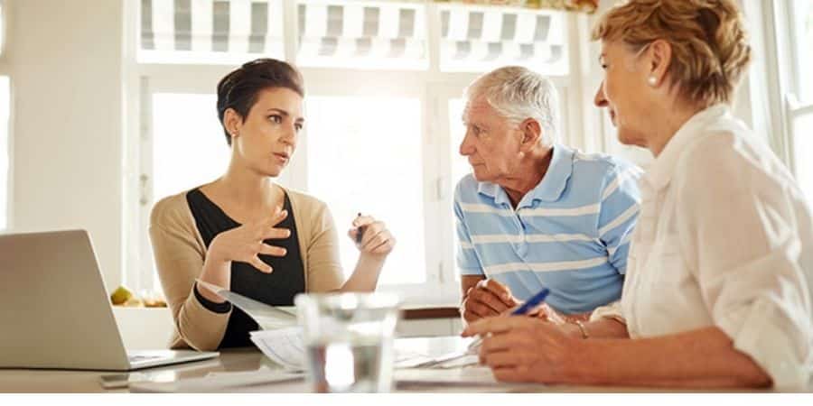 A financial advisor discussing plans with a senior couple at a table.