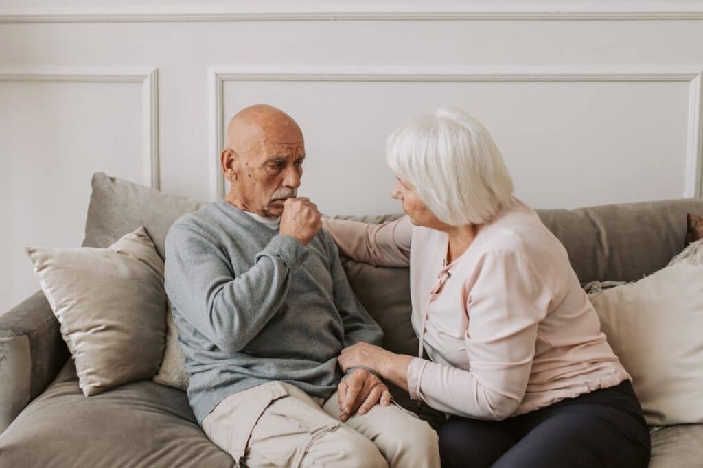 An elderly couple sharing a moment of comfort on a couch.