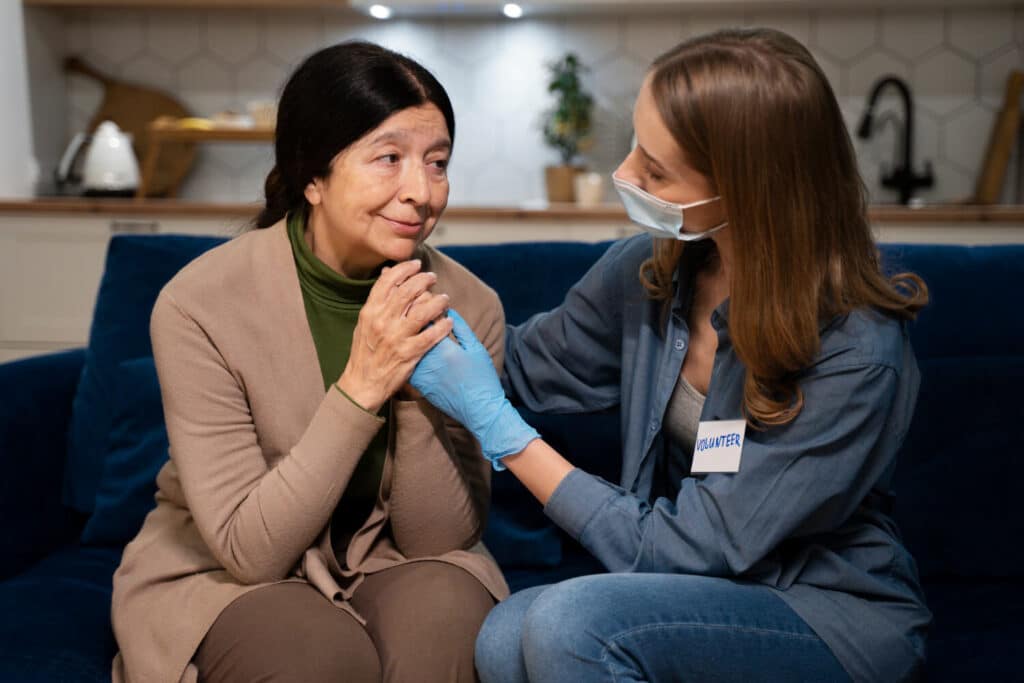 A volunteer comforting an elderly woman during a home visit.