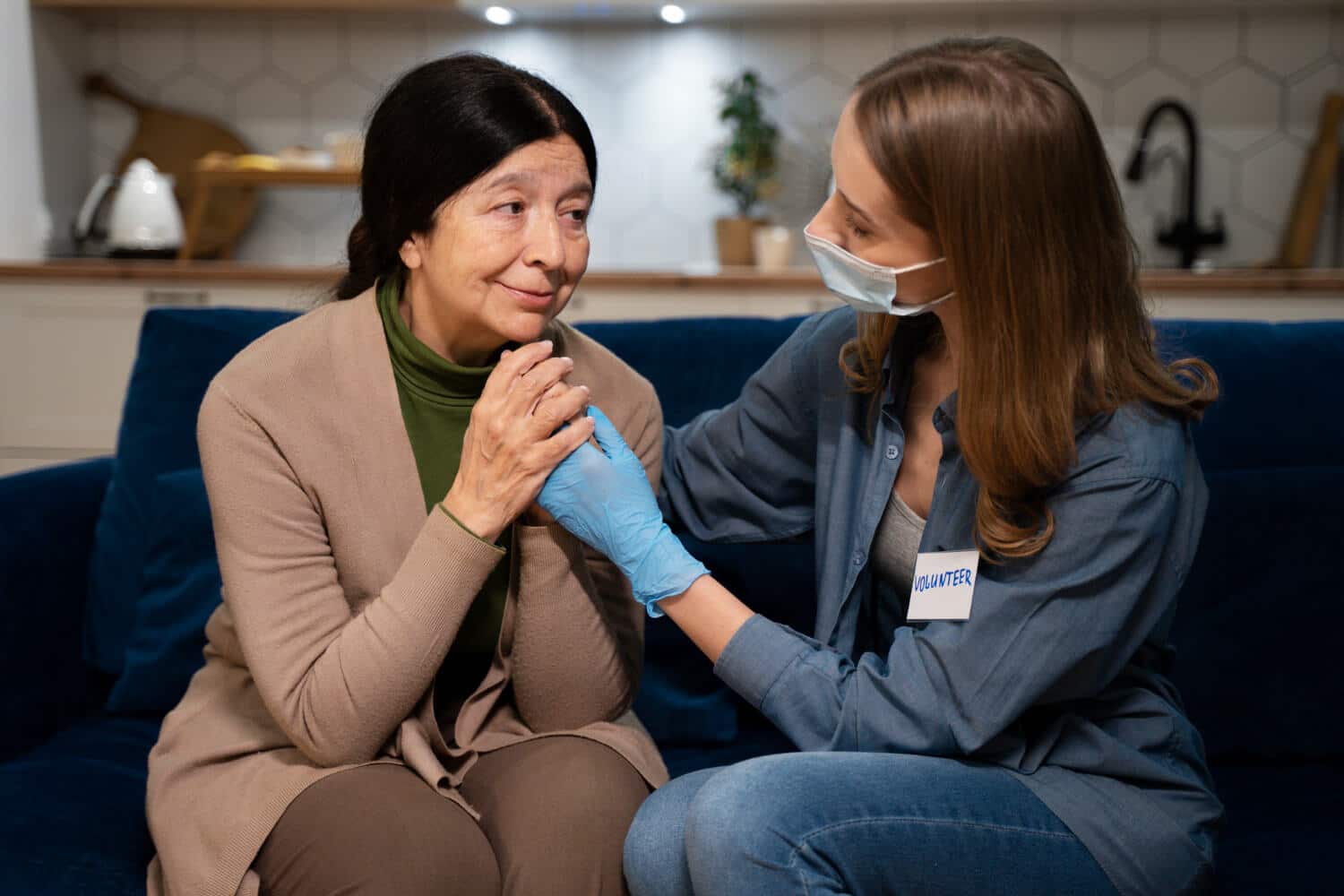 A volunteer comforting an elderly woman during a home visit.