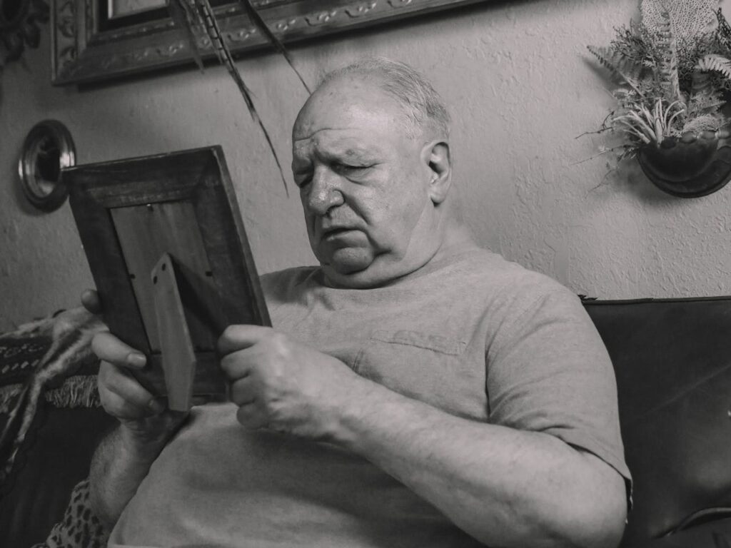 An elderly man deeply focused on a photo frame, evoking nostalgia.