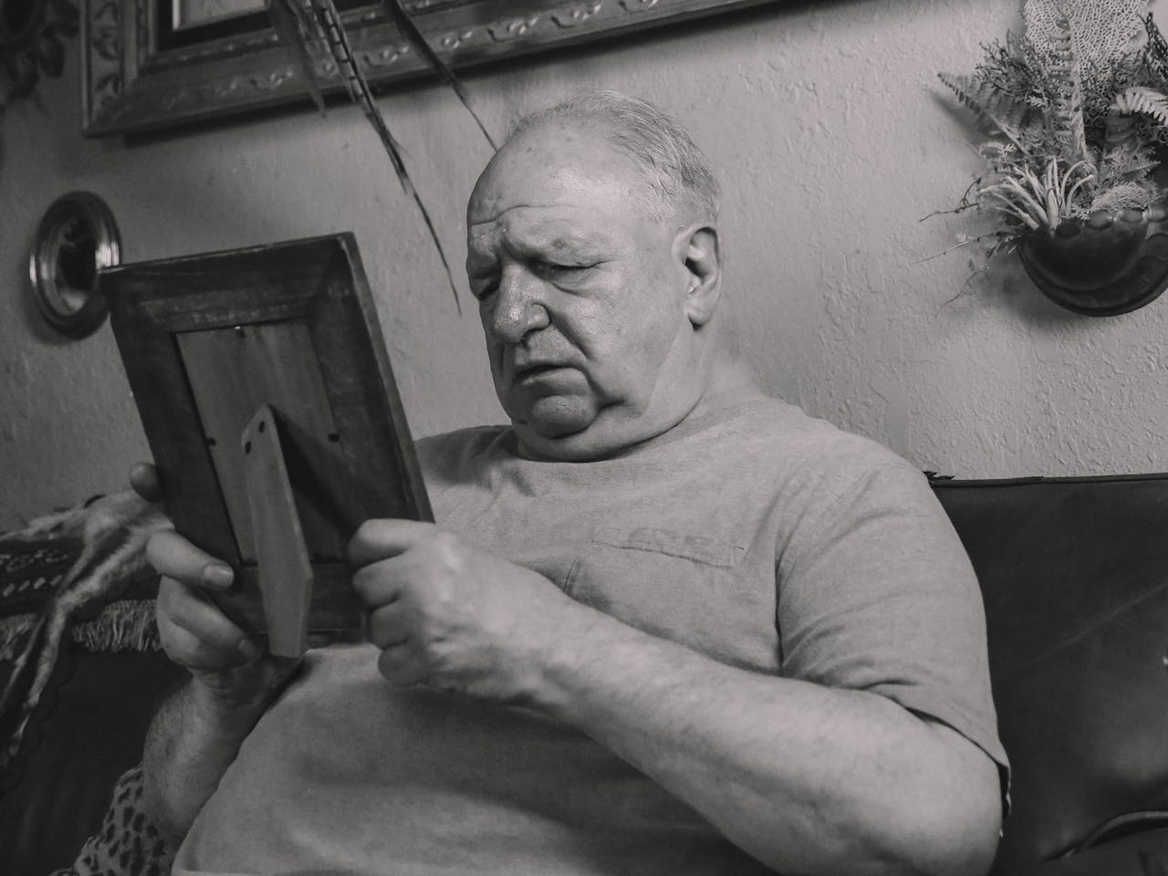 An elderly man deeply focused on a photo frame, evoking nostalgia.