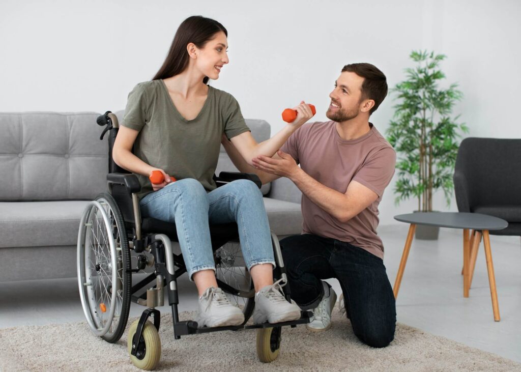 woman in a wheelchair exercising with dumbbells while being assisted by a man