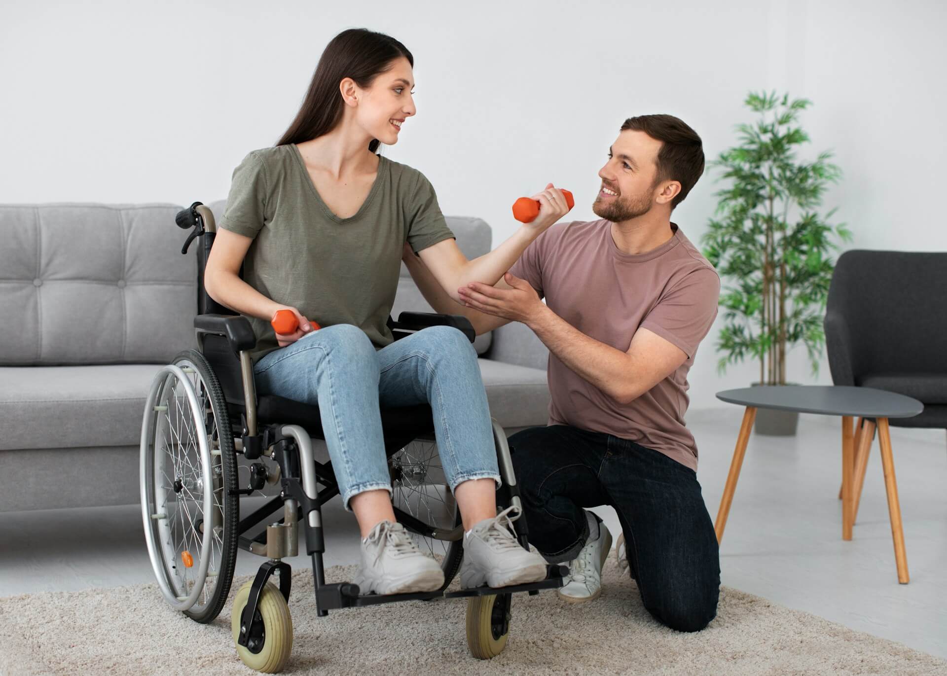 woman in a wheelchair exercising with dumbbells while being assisted by a man