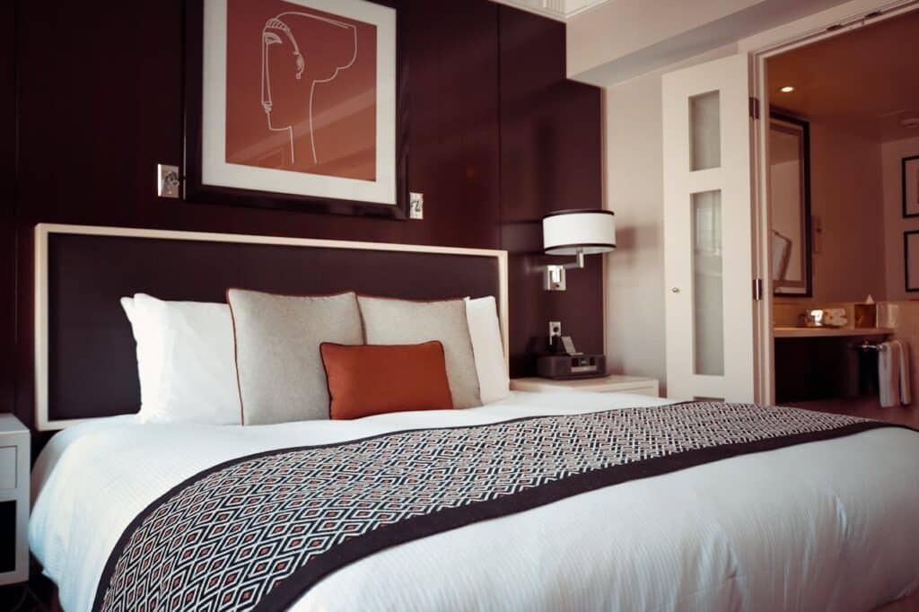 A stylish modern bedroom featuring a neatly made bed with decorative pillows and contemporary artwork.