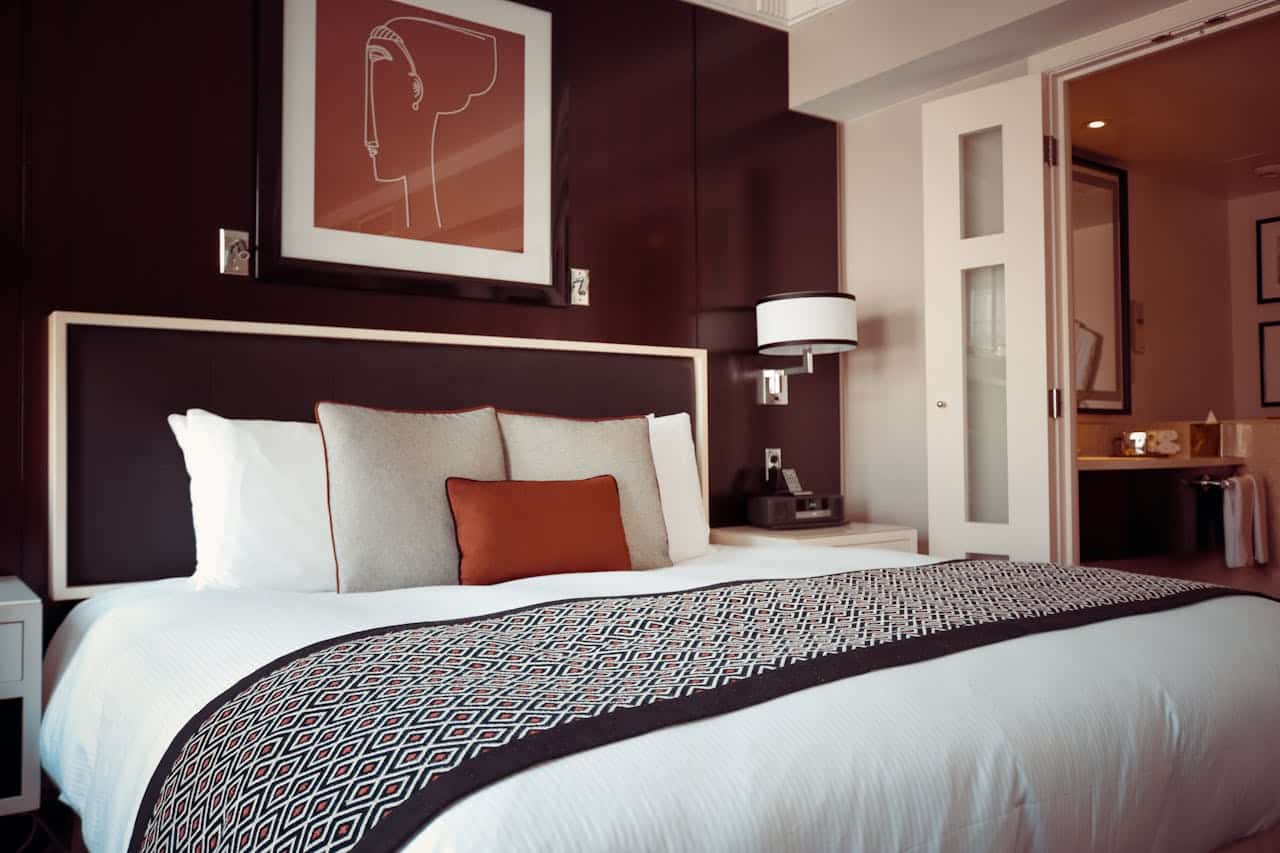 A stylish modern bedroom featuring a neatly made bed with decorative pillows and contemporary artwork.